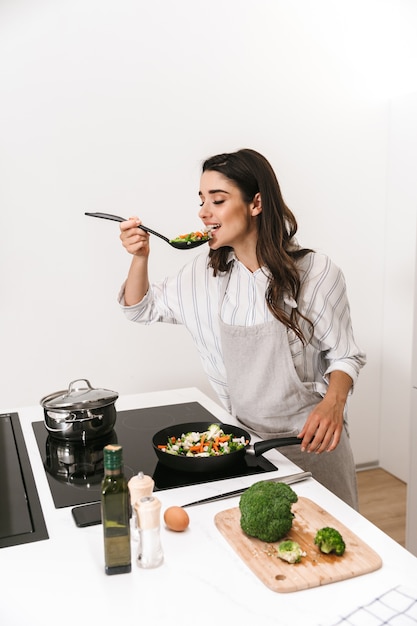 Hermosa joven cocinando una cena saludable en la cocina