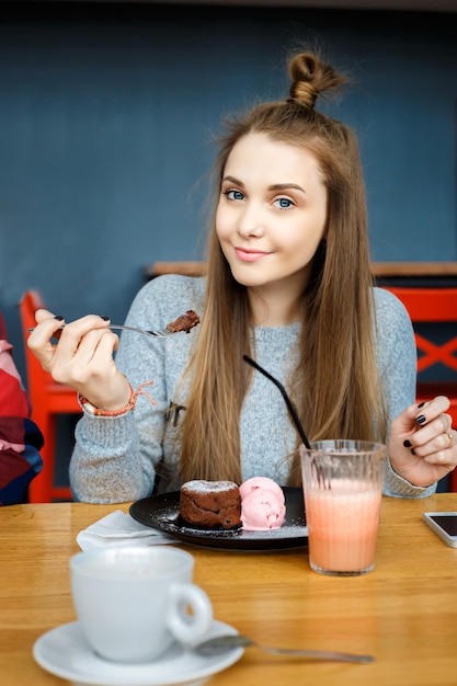 Hermosa joven come desierto en café