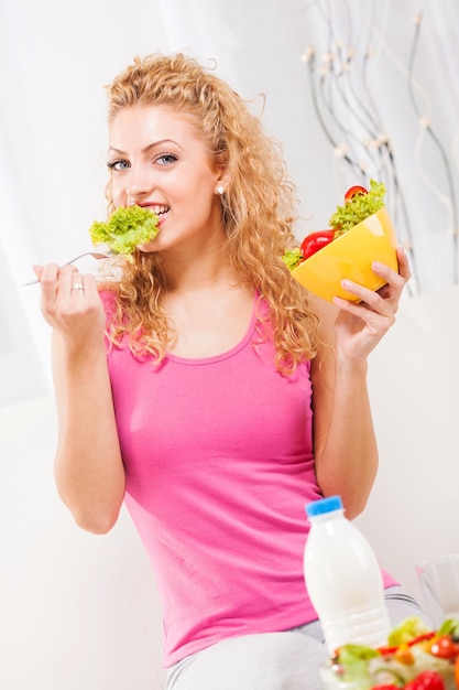 Hermosa joven comiendo ensalada