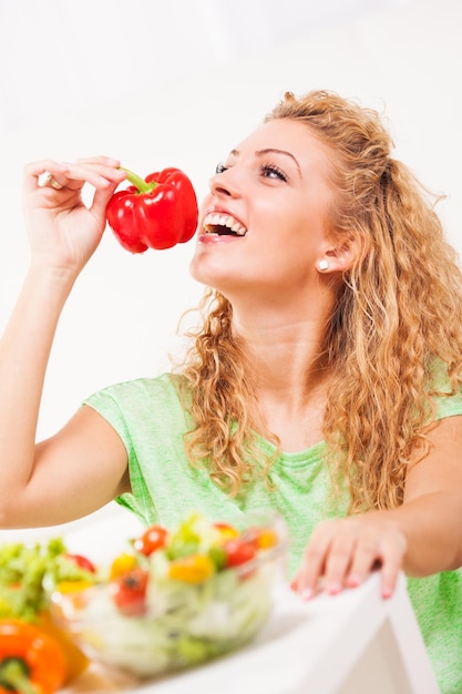 Hermosa joven comiendo pimiento rojo