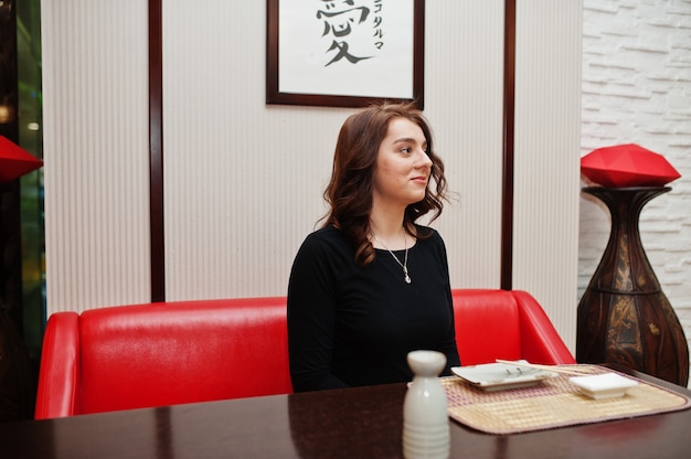 Una hermosa joven comiendo sushi en el restaurante tradicional japonés.