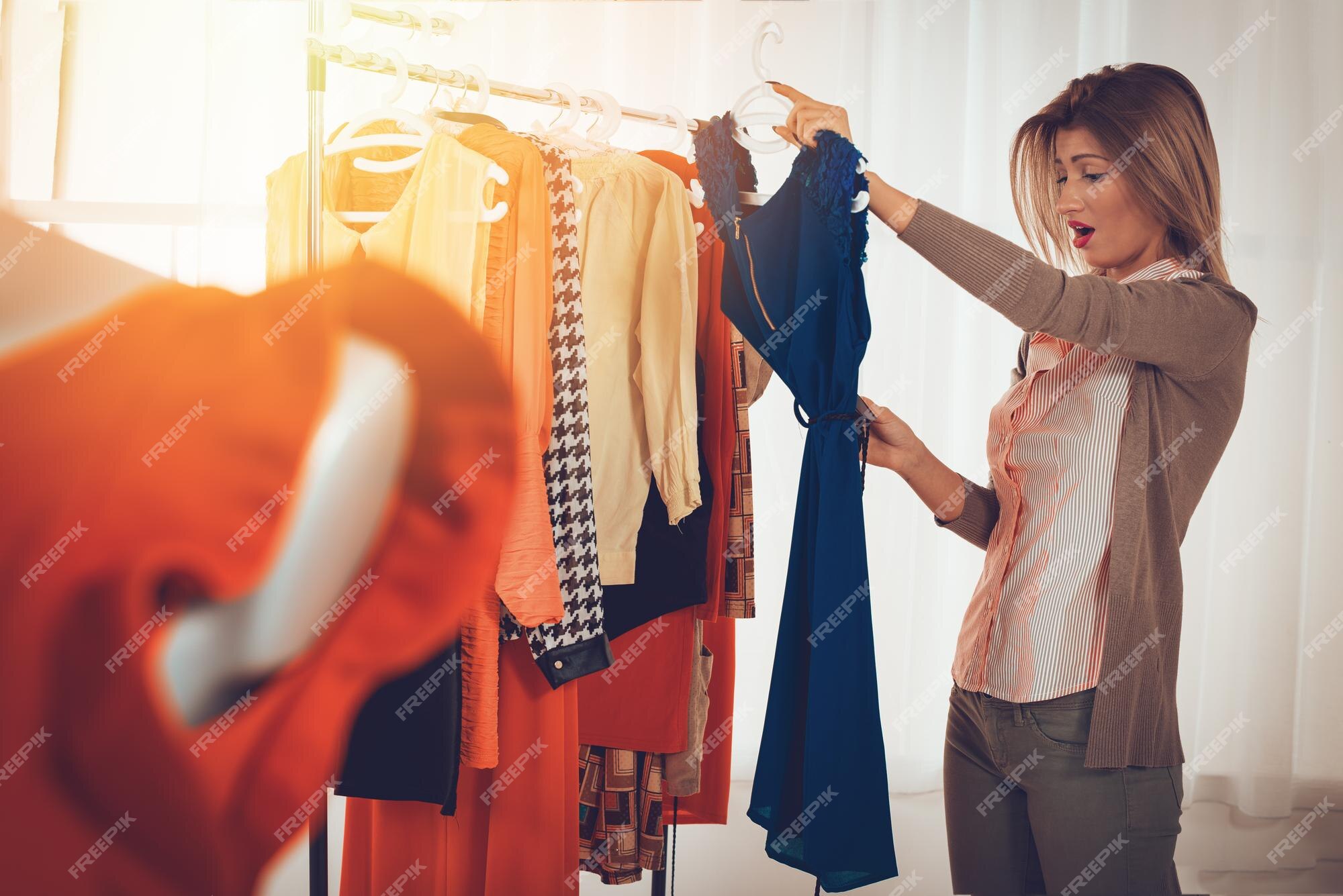 Hermosa compradora sorprendida por el precio del vestido. ella está ropa en la oficina diseñador de moda. en primer plano se puede ver un vestido sobre enfoque selectivo.