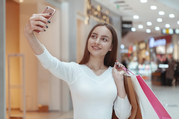 Hermosa joven de compras en el centro comercial local