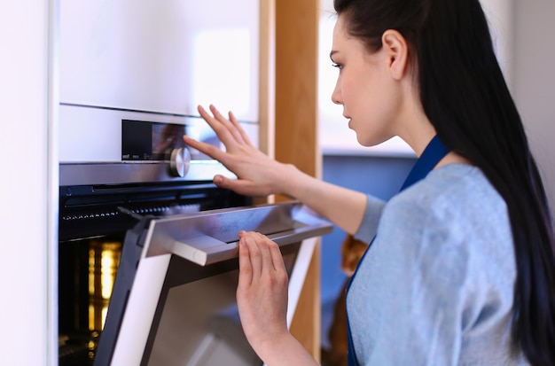 Hermosa joven comprobando cómo le va a su pastel en el horno