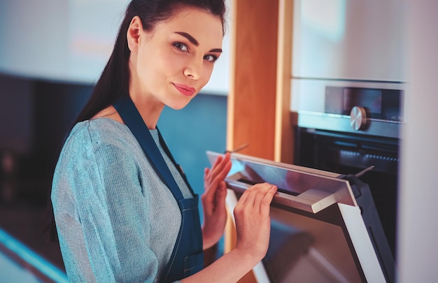 Hermosa joven comprobando cómo le va a su pastel en el horno