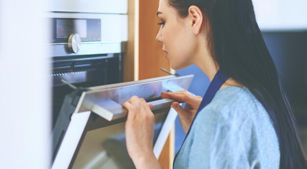 Hermosa joven comprobando cómo le va a su pastel en el horno