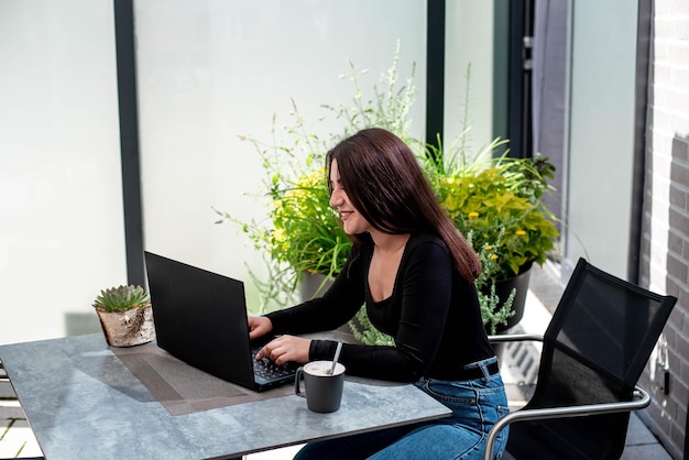 hermosa joven con una computadora portátil se sienta en una mesa y trabaja