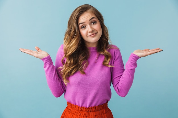 Hermosa joven confundida con ropa casual que se encuentran aisladas sobre la pared azul