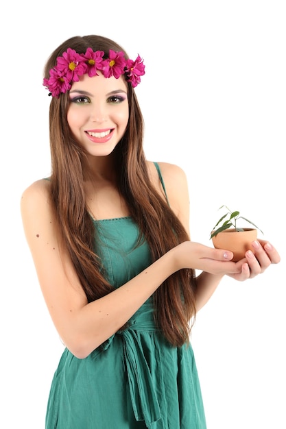 Hermosa joven con corona decorativa en la cabeza sosteniendo una olla con planta verde, aislado en blanco