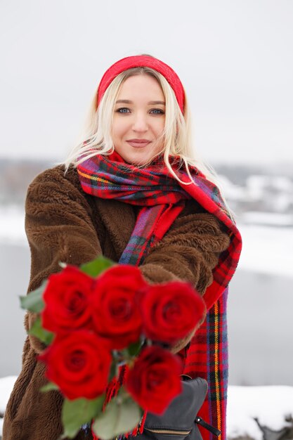 Hermosa joven da un ramo de rosas rojas en el día de San Valentín