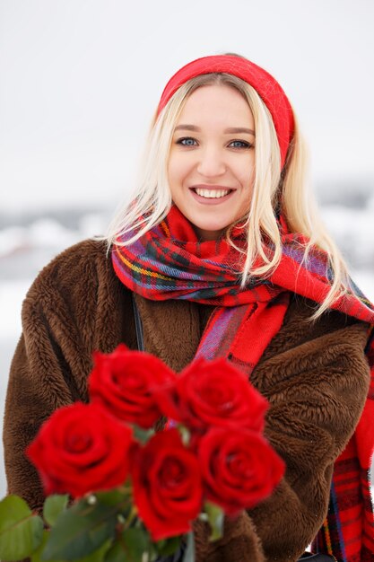 Hermosa joven da un ramo de rosas rojas en el día de San Valentín