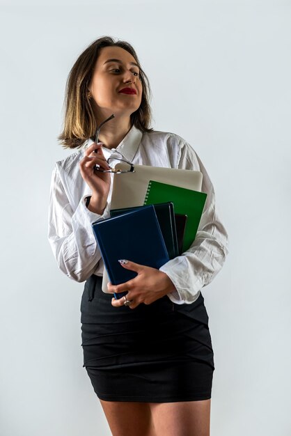 Hermosa joven dama de negocios de pie con documentos aislados en fondo blanco