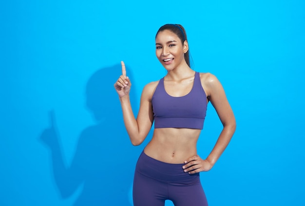 Hermosa joven deportista asiática haciendo deporte usando ropa deportiva sobre fondo azul.