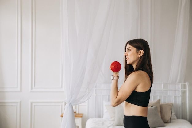 Hermosa joven deportiva haciendo ejercicios con pesas en casa foto de alta calidad