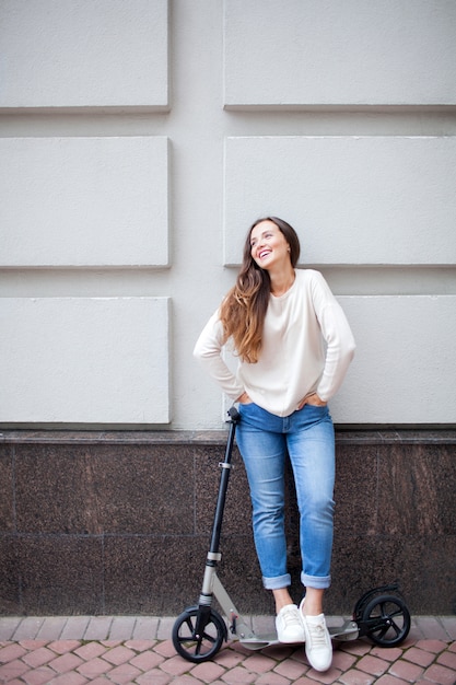 Foto hermosa joven se detuvo mientras montaba el scooter.