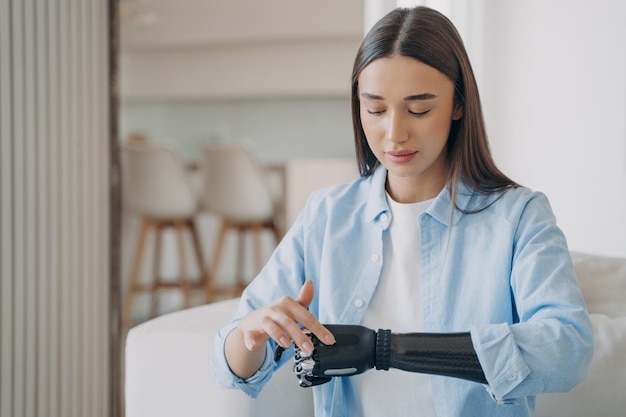 Hermosa joven discapacitada con brazo protésico biónico aprendiendo a encender prótesis de alta tecnología