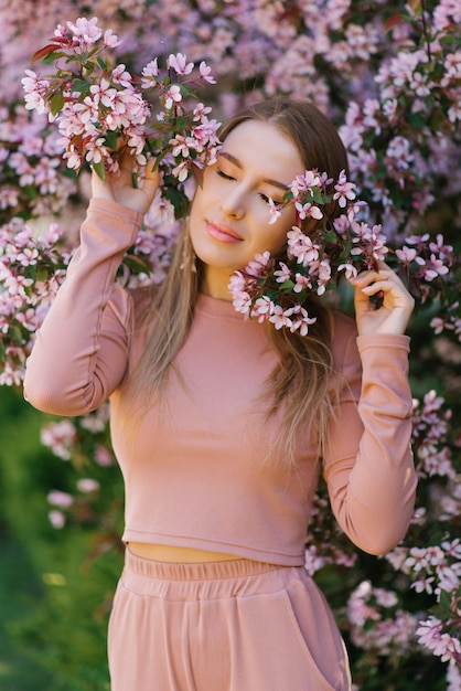 Una hermosa joven disfruta de la vida en un jardín floreciente de primavera con el telón de fondo de los manzanos florecientes