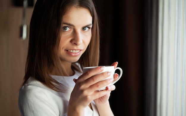 Hermosa joven disfrutando de un delicioso café en casa