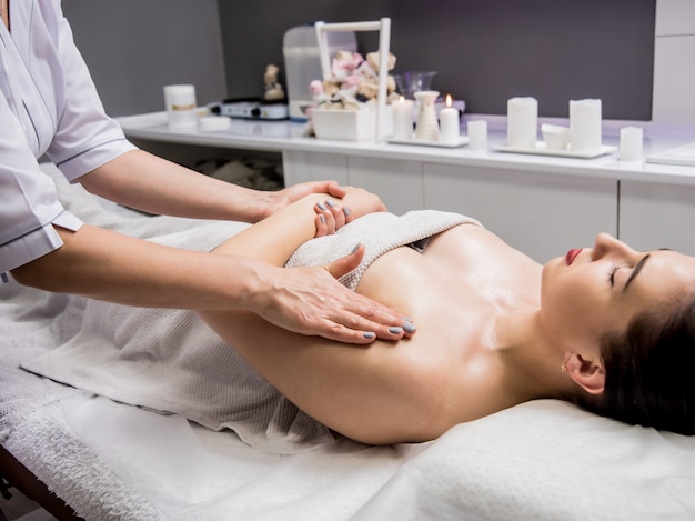 Hermosa joven disfrutando de un masaje en el salón de spa. Cosmetología