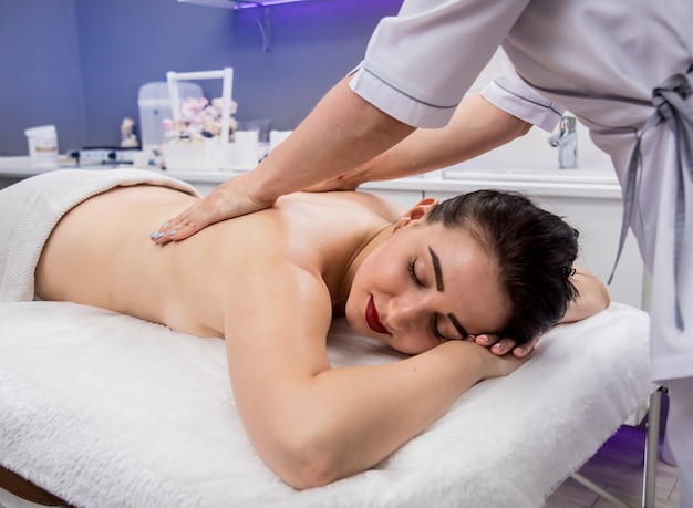 Hermosa joven disfrutando de un masaje en el salón de spa. Cosmetología