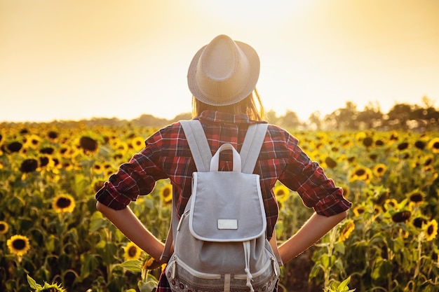 Hermosa joven disfrutando de la naturaleza en el campo de girasoles al atardecer