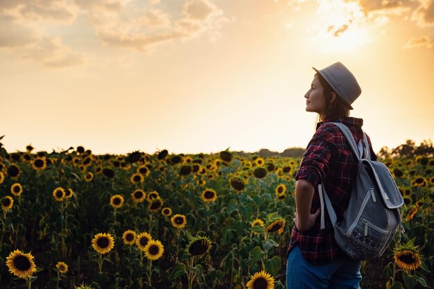 Hermosa joven disfrutando de la naturaleza en el campo de girasoles al atardecer