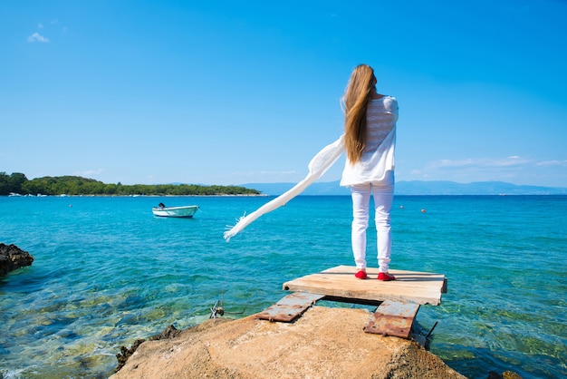 Una hermosa joven disfrutando del viento y el clima en el verano en el océano.