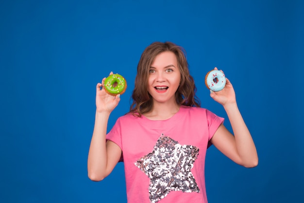 Hermosa joven divertida con donas en azul.