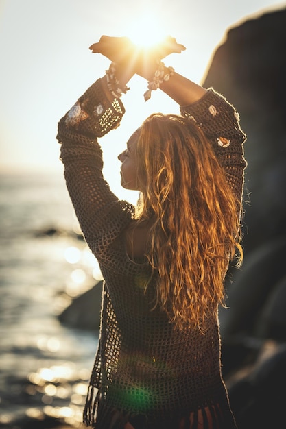 Una hermosa joven se divierte y se relaja en la playa al atardecer.