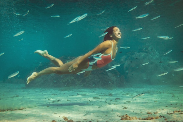 Una hermosa joven se divierte en las vacaciones de verano explorando el fondo marino durante el buceo en el mar.