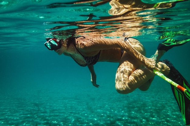 Una hermosa joven se divierte en las vacaciones de verano explorando el fondo marino durante el buceo en el mar.