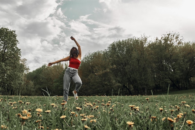 Foto hermosa joven divirtiéndose en un parque de verano en la hierba y un prado de diente de león.fondo de verano