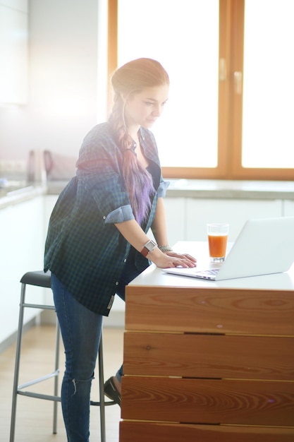 Hermosa joven doctora sonriente sentada en el escritorio y escribiendo