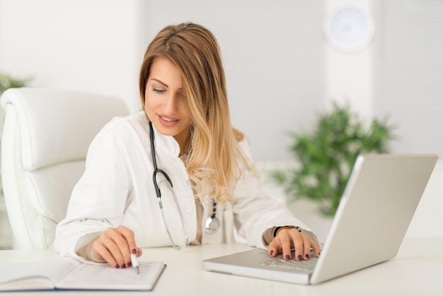 Hermosa joven doctora en su consultorio y trabajando.