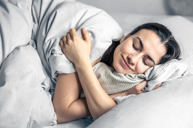 Una hermosa joven duerme en una cama blanca