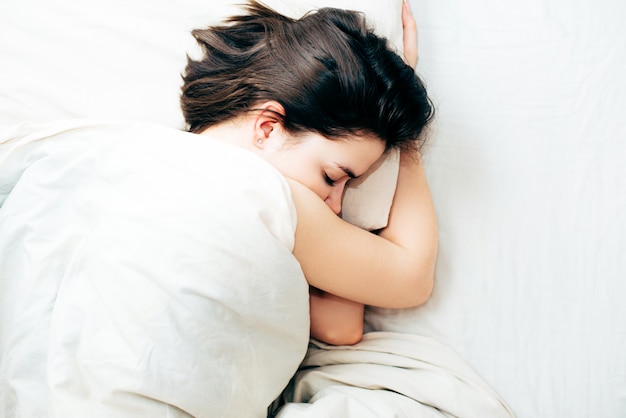 Hermosa joven durmiendo mientras está acostado en la vista superior de su cama