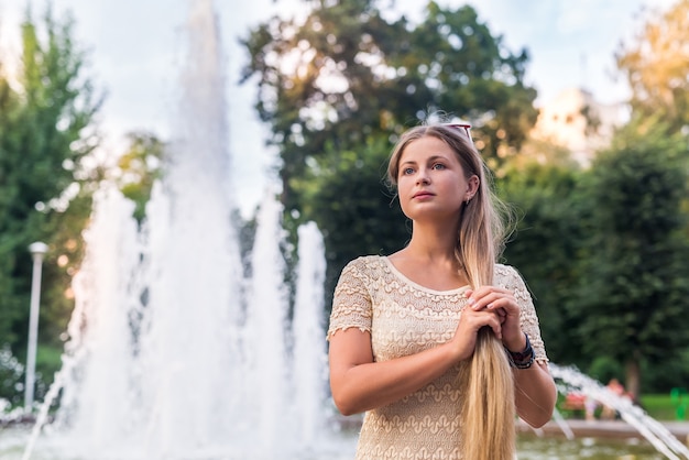 Hermosa joven elegante posando en la ciudad cerca de fuentes