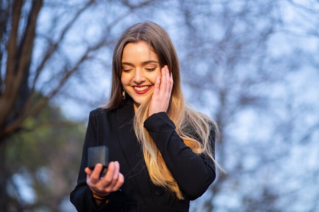 Hermosa joven en elegante traje mirando el anillo de bodas en caja