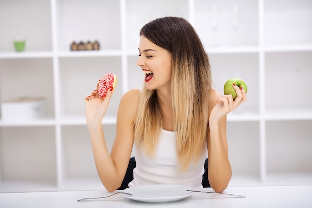 hermosa joven eligiendo entre comida sana y comida chatarra