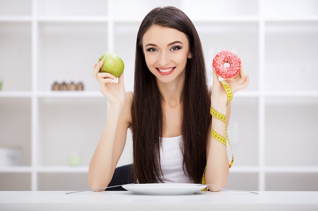 hermosa joven eligiendo entre comida sana y comida chatarra