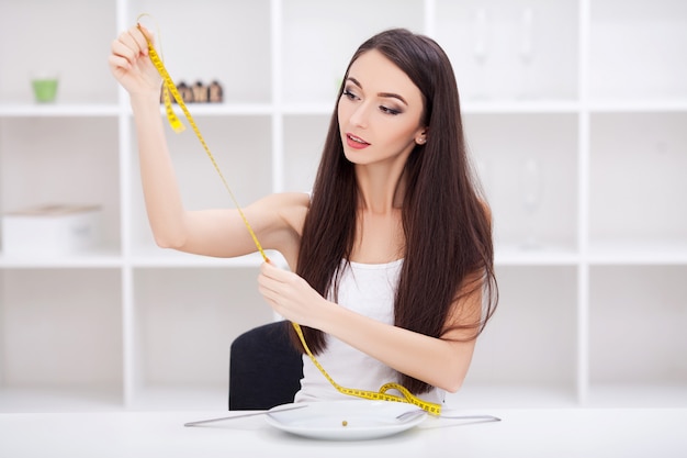 Hermosa joven eligiendo entre frutas y comida chatarra