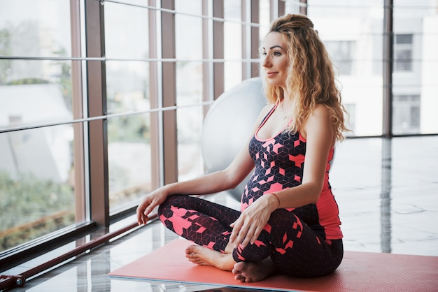 Hermosa joven embarazada meditando en el pasillo.