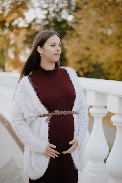 Hermosa joven embarazada en el parque de la ciudad