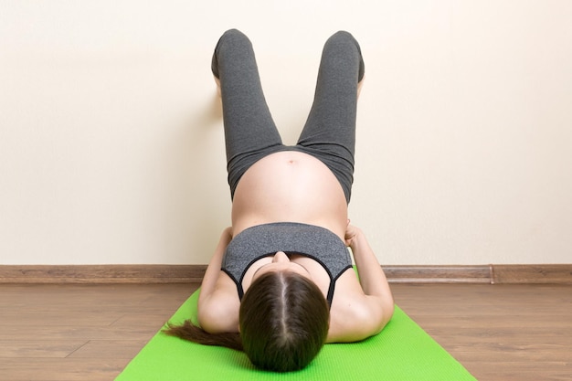 hermosa joven embarazada sentada en una alfombra en la postura de yoga en el hogar embarazo Yoga y fitness concepto en el tiempo de coronavirus