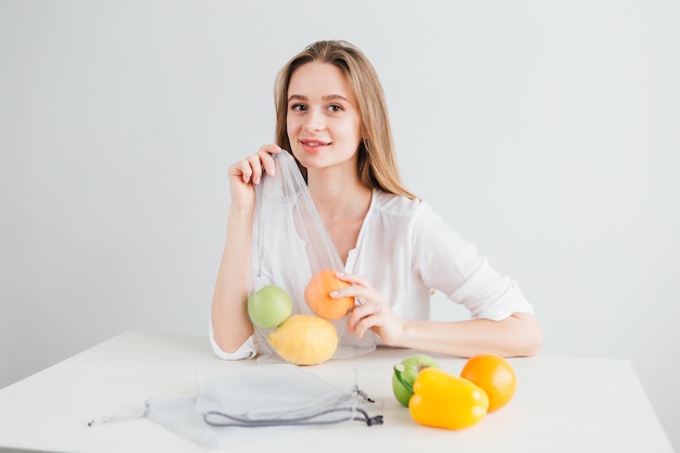 Hermosa joven empaca las verduras y frutas en una bolsa de tela reutilizable. El concepto de cero residuos. Viraje.