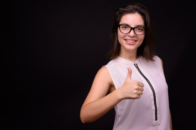 Hermosa joven empresaria contra la pared negra