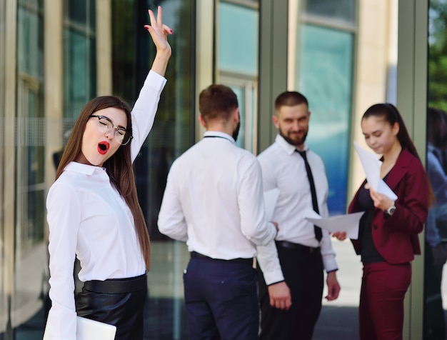 Hermosa joven empresaria es feliz en el contexto de un edificio de oficinas y colegas