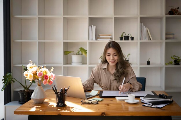 Hermosa joven empresaria que trabaja con una computadora portátil en un lugar de trabajo moderno