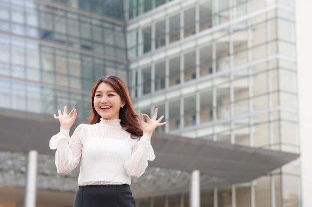 Hermosa joven empresaria seria y segura de sí misma que muestra un gesto correcto en un edificio de oficinas al aire libre