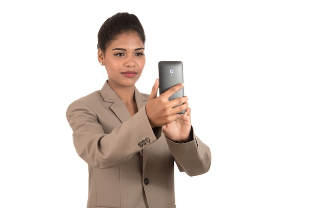 Hermosa joven empresaria con smartphone para tomar fotos selfie aislado sobre fondo blanco.